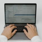 Close-up of hands coding on a laptop, showcasing software development in action.