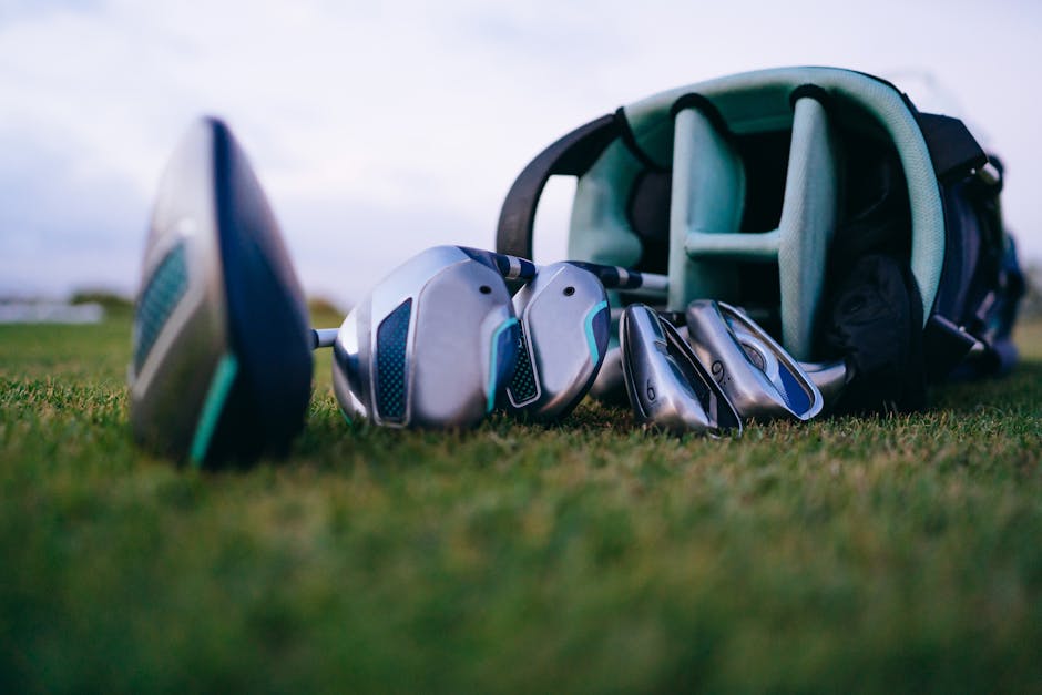 Set of golf clubs lies on a grass field, perfect for golfing enthusiasts.
