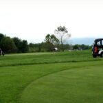 Golfers enjoying a day at a lush green golf course in Crozet, VA, under a cloudy sky.