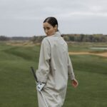 A female golfer walking confidently on a lush golf course during the day.