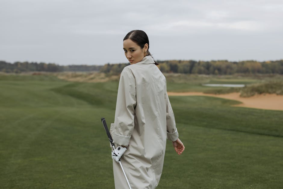 A female golfer walking confidently on a lush golf course during the day.