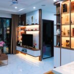 Sleek modern living room with illuminated shelves, TV unit, and floral decor.