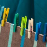 Bright clothes pegs holding striped towels on an outdoor clothesline, showcasing a colorful laundry scene.