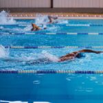 Swimmers in action during a race in an indoor swimming pool, showcasing athleticism.