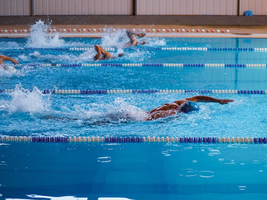 Swimmers in action during a race in an indoor swimming pool, showcasing athleticism.