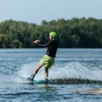 An adult male enjoying a thrilling wakeboarding session on a serene lake.