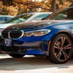 Blue BMW 330i parked outdoors in Arlington, Texas, under sunny skies.