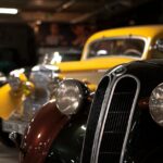 Detailed view of classic vintage cars in a dimly lit automotive museum.
