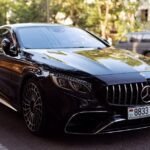 Elegant black luxury car parked on urban road, showcasing sleek design and polished exterior.