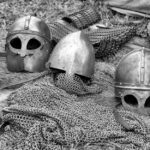 Close-up of historical medieval helmets and armor in black and white.