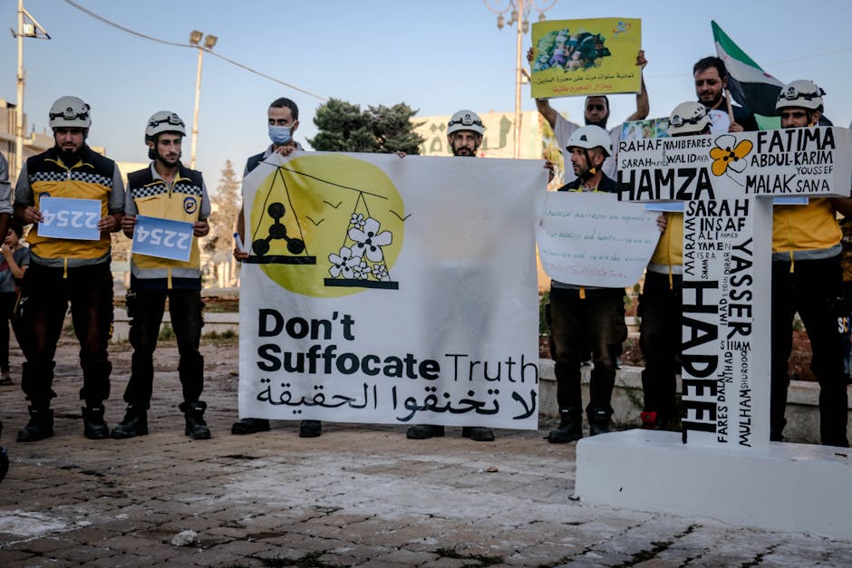 Protest in Idlib, Syria against chemical attacks, featuring banners and activists in protective gear.